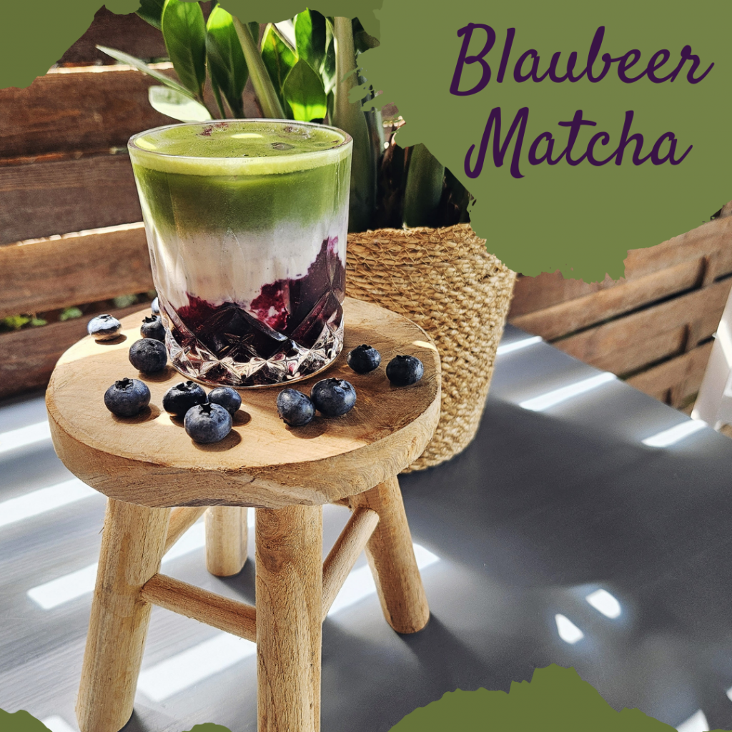 Blaubeer Matcha Latte auf einem dekorierten Tisch mit frischen Beeren.