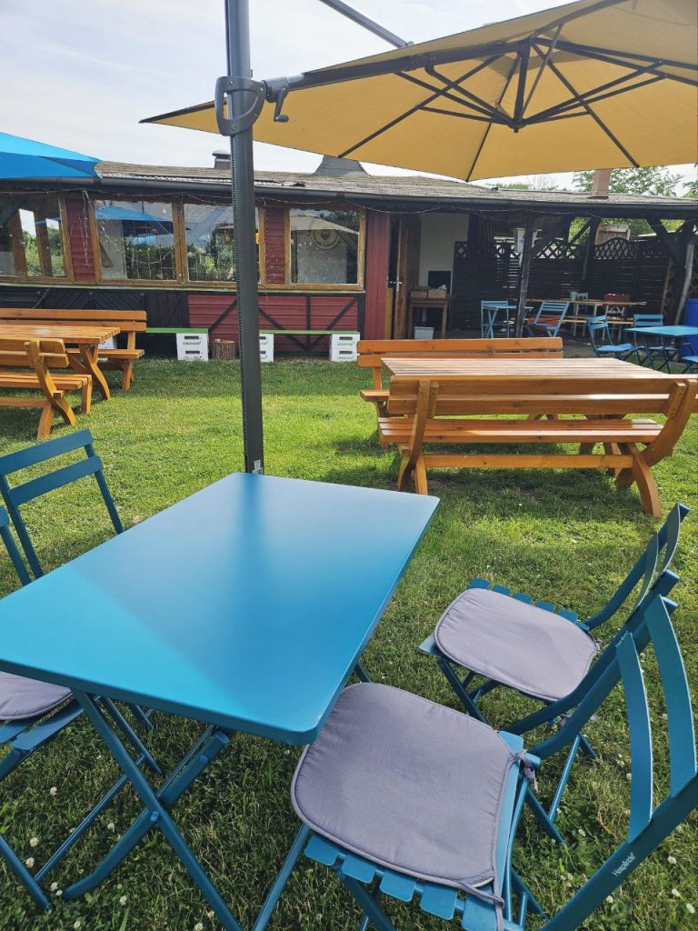 Außenbereich mit grüner wiese und farbenfohen Tischen vor dem Wombats Café